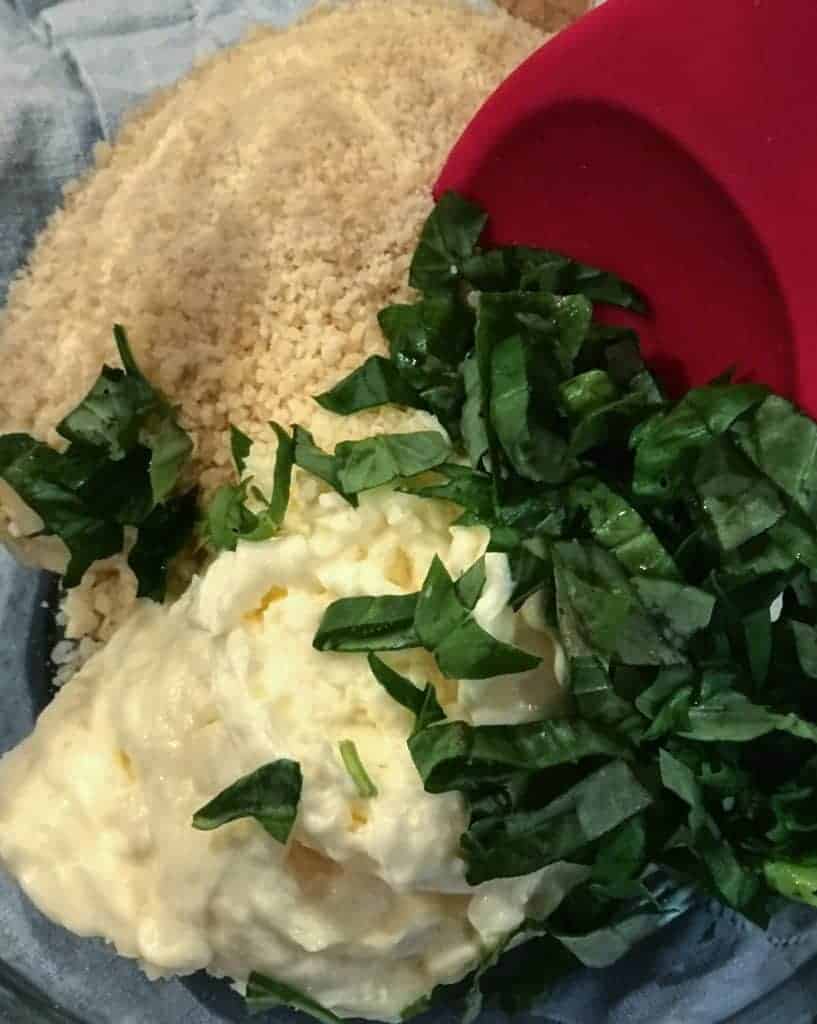 Bowl of ingredients featuring mayonnaise, Parmesan, garlic, and basil