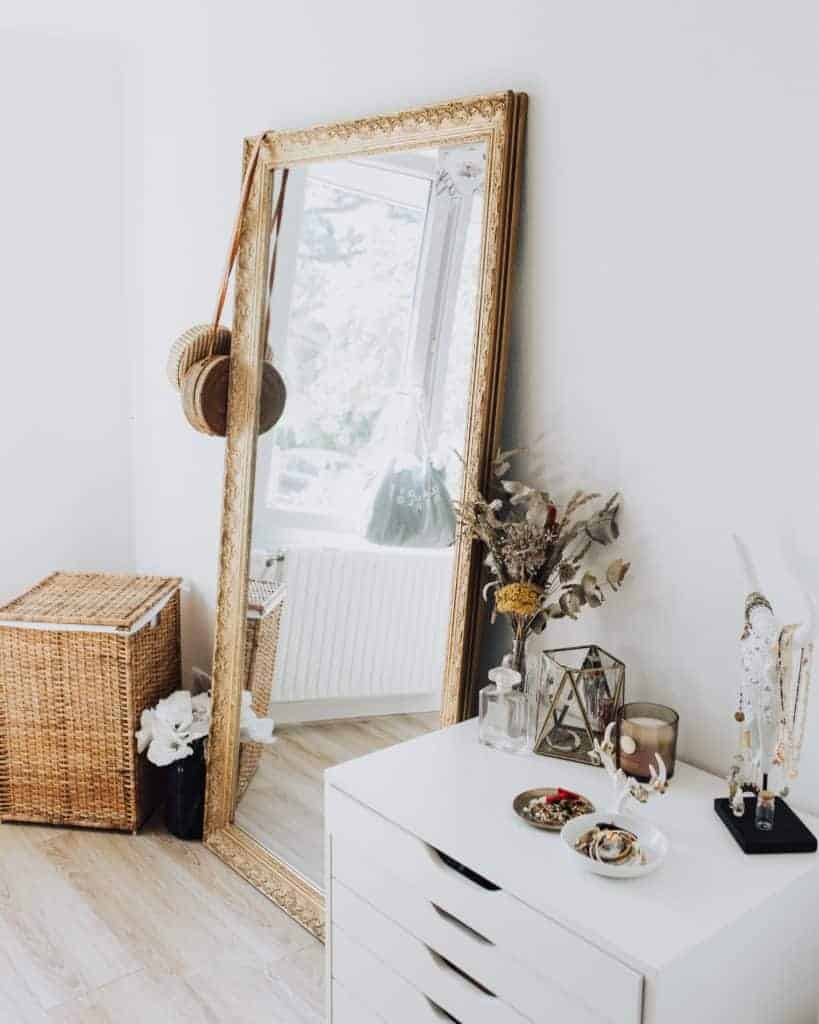 Little Spacea - Tall mirror leaning against wall beside traditional basket and table.