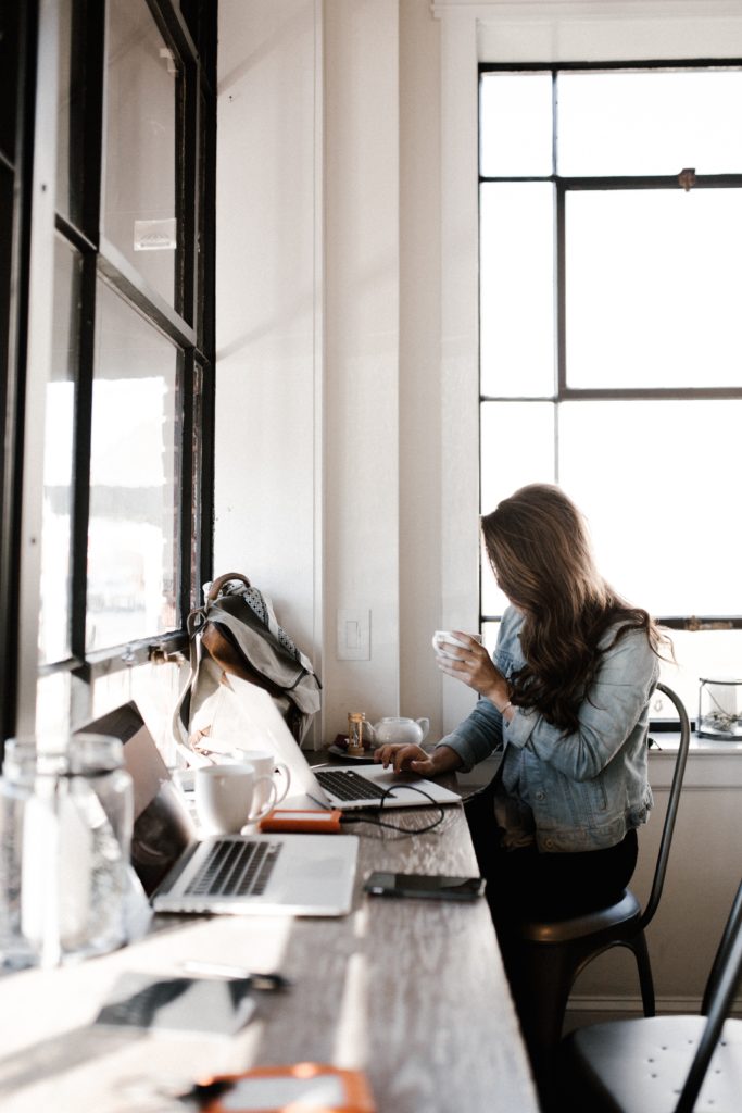 Blogging - Woman sitting in a coffee shop with a laptop blogging
